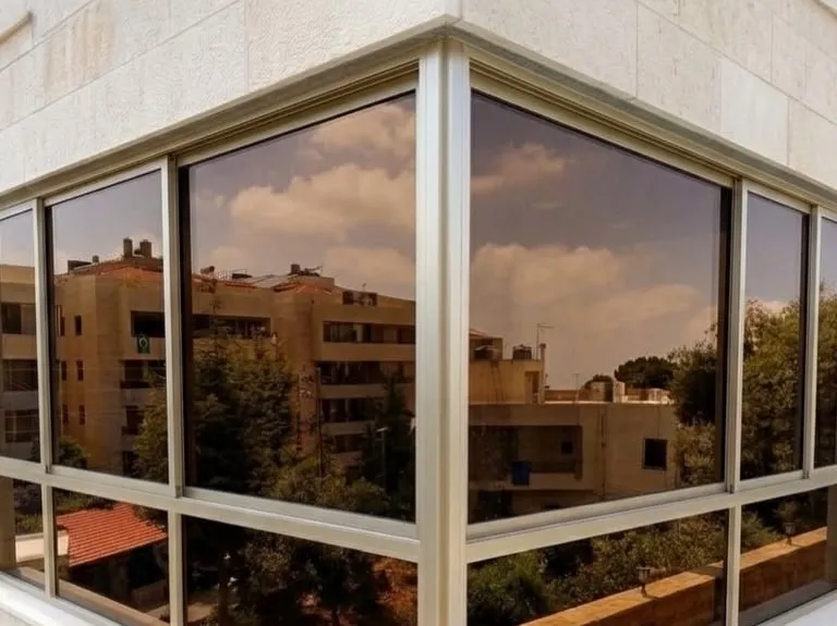 Champagne aluminium corner window in a limestone facade reflecting the neighbouring buildings