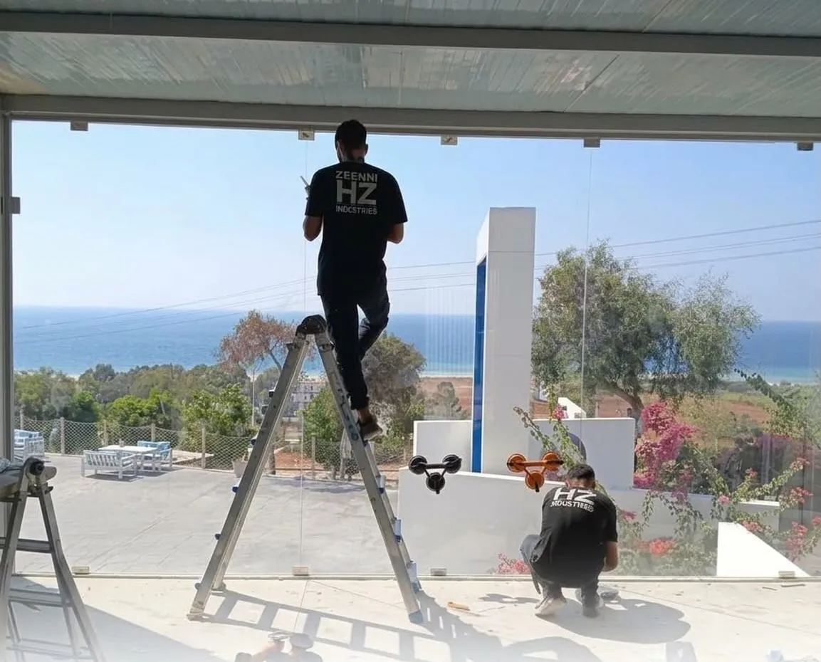 HZ Zeenni installers fitting frameless glass under a seaside pergola